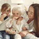 Mother and kids enjoying cookies in a warm, cozy kitchen setting.